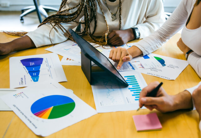 business team meeting with stats and review graphs of company target, goals or market research with data analysis. Above, table or paperwork report of growth, progress or startup performance analytics